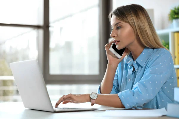 Vrouwelijke business trainer praten over de telefoon tijdens het werken met laptop in het kantoor — Stockfoto