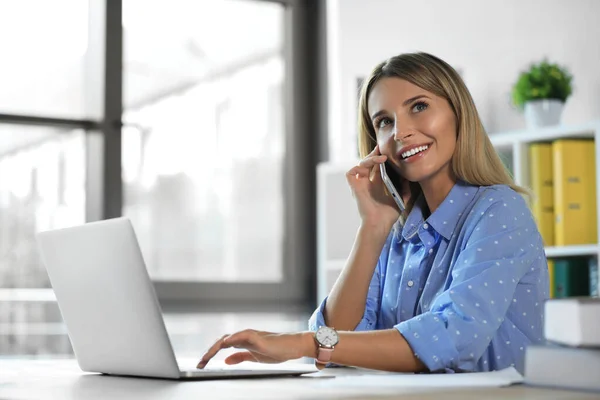 Business trainer donna che parla al telefono mentre lavora con il computer portatile in ufficio — Foto Stock