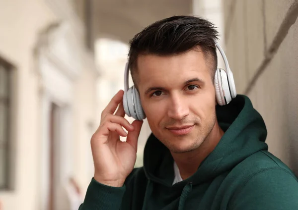 헤드폰을 끼고 밖에서 음악을 듣고 있는 잘생긴 청년의 사진 — 스톡 사진