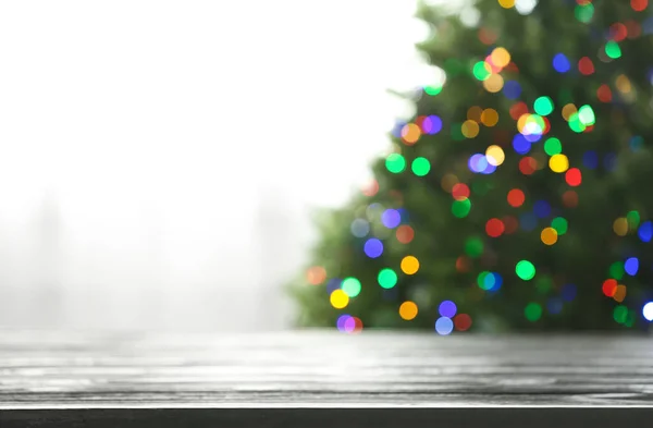 Mesa vacía y abeto borroso con luces de Navidad de colores en el fondo, efecto bokeh. Espacio para el diseño — Foto de Stock