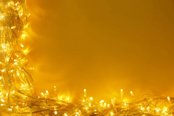 Glowing Christmas lights on yellow background, top view. Space for text — Stock Photo, Image