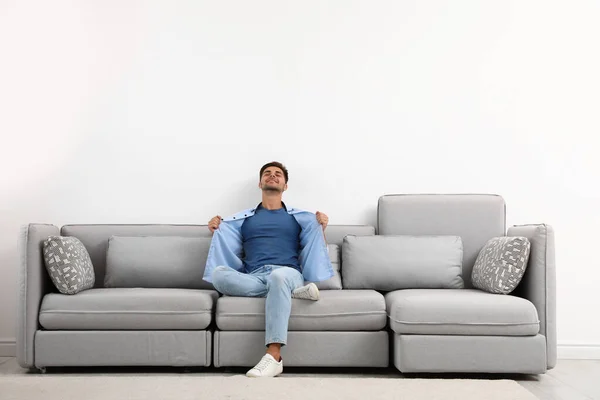 Jeune homme relaxant sur canapé contre mur blanc — Photo