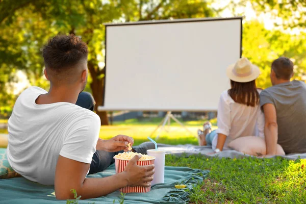 Young man with popcorn watching movie in open air cinema. Space for text — Stock Photo, Image