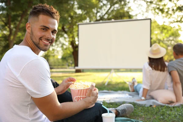 Young man with popcorn watching movie in open air cinema. Space for text — Stock Photo, Image