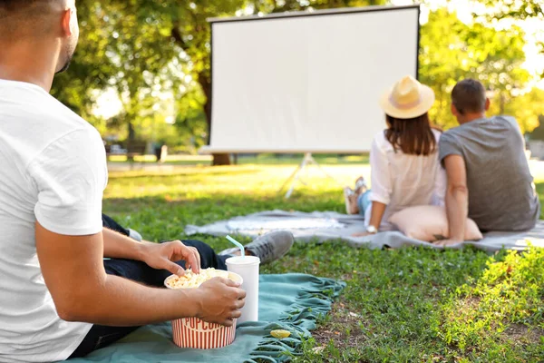 Young man with popcorn watching movie in open air cinema, closeup. Space for text — Stock Photo, Image