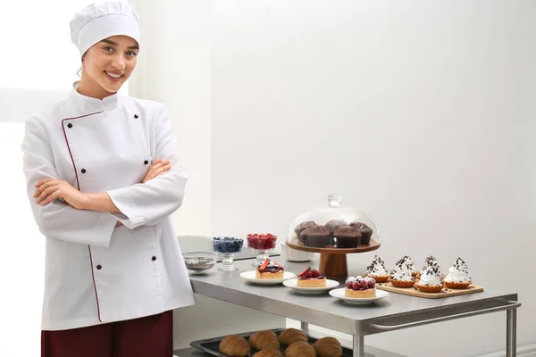 Chef femminile vicino al tavolo con diversi dolci in cucina — Foto Stock