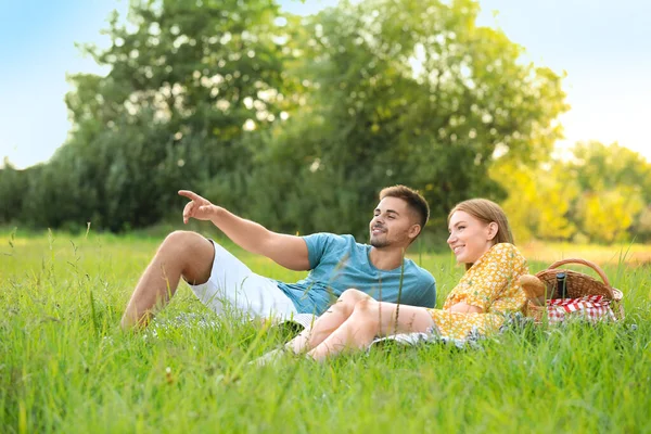 Feliz pareja joven haciendo un picnic sobre hierba verde en el parque — Foto de Stock