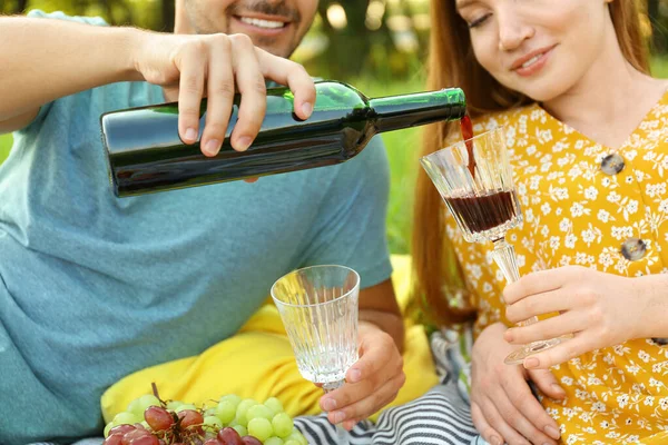 Şarap ve gözlüklü genç çift dışarıda piknik yapıyor, yakın plan. — Stok fotoğraf