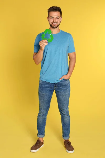 Giovane uomo con simbolo di riciclaggio su sfondo giallo — Foto Stock