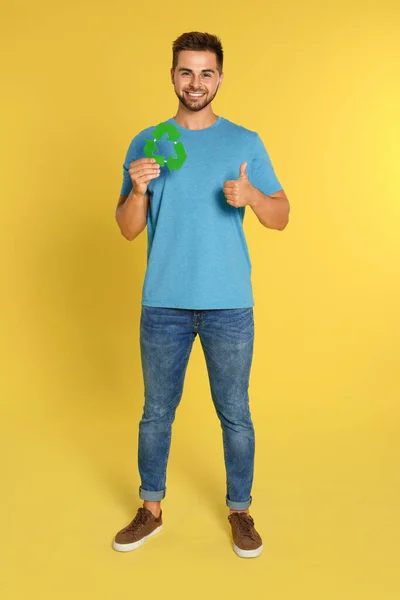 Молодий чоловік з символом переробки на жовтому тлі — стокове фото