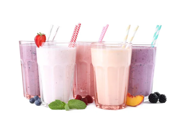 Verschiedene frische leckere Milchshakes in Gläsern mit Zutaten auf weißem Hintergrund — Stockfoto