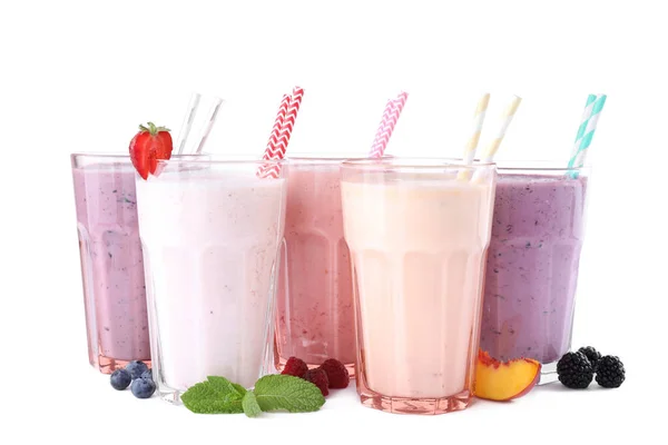 Different fresh tasty milk shakes in glasses with ingredients on white background — Stock Photo, Image