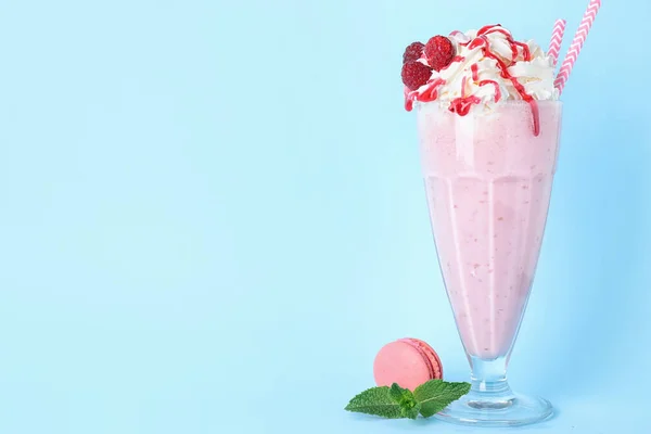 Tasty raspberry milk shake in glass and macaron on light blue background. Space for text — Stock Photo, Image