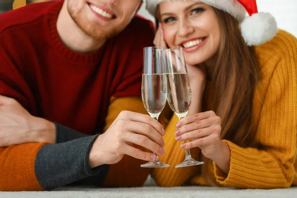 Šťastný mladý pár s sklenicemi šampaňského doma, soustřeďte se na ruce. Vánoční oslava — Stock fotografie
