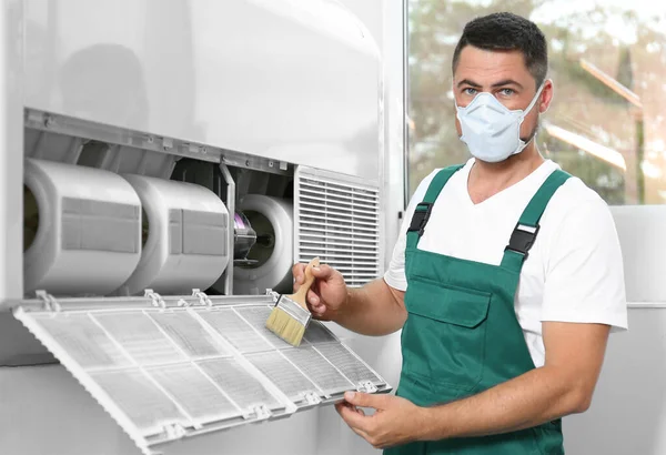 Professional male technician cleaning air conditioner indoors. Repair and maintenance — Stock Photo, Image