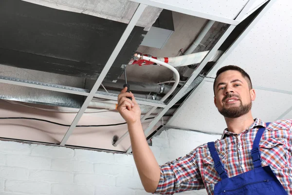 Técnico profesional reparando el aire acondicionado montado en el techo en interiores —  Fotos de Stock