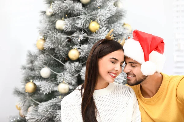 Happy young couple near Christmas tree at home — Stock Photo, Image