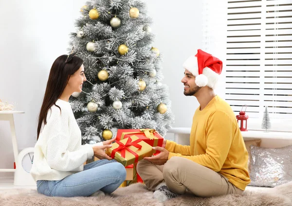 Mutlu genç çift evde Noel hediyelerini değiş tokuş ediyor. — Stok fotoğraf