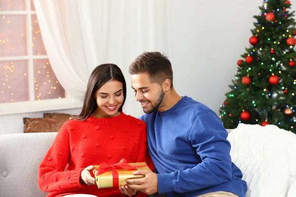 Šťastný mladý pár s vánočním dárkem doma — Stock fotografie