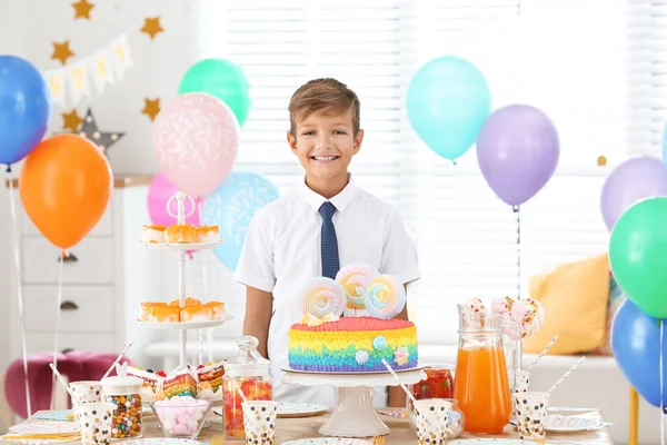 Happy boy at table with treats in room decorated for birthday party — Stock Photo, Image