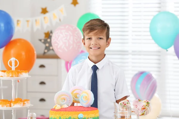 Happy boy at table with treats in room decorated for birthday party — Stock Photo, Image