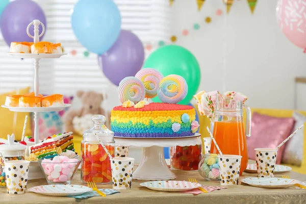 Яскравий торт на день народження та інші частування на столі в декорованій кімнаті — стокове фото