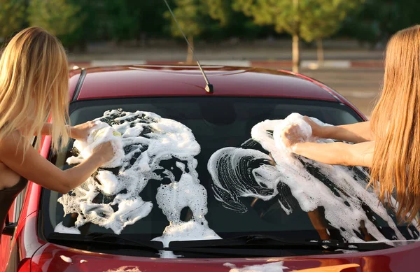 Young women washing car with sponges outdoors — Zdjęcie stockowe