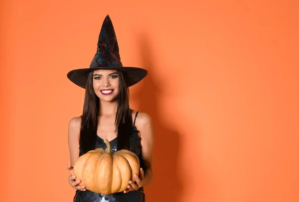 Hermosa mujer con traje de bruja con calabaza para la fiesta de Halloween sobre fondo amarillo, espacio para el texto —  Fotos de Stock