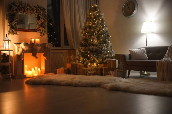 Stijlvol interieur met prachtige kerstboom en decoratieve open haard 's nachts — Stockfoto