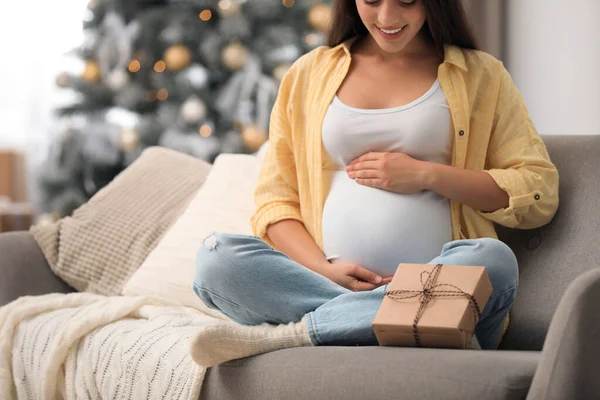 Mulher grávida feliz com caixa de presente na sala de estar decorada para o Natal, close-up. Bebê esperado — Fotografia de Stock