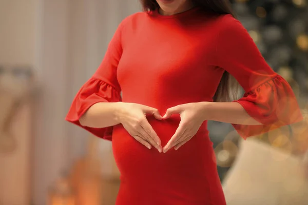 Zwangere vrouw in kamer ingericht voor Kerstmis, close-up. Verwachte baby — Stockfoto
