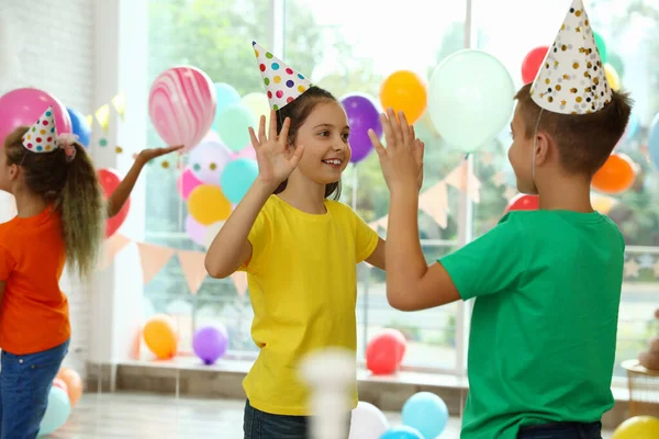 Happy children playing at birthday party in decorated room — Stock Photo, Image