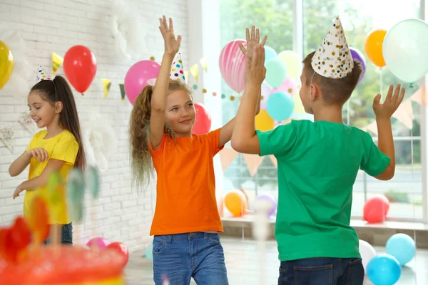 Niños felices jugando en la fiesta de cumpleaños en la habitación decorada —  Fotos de Stock
