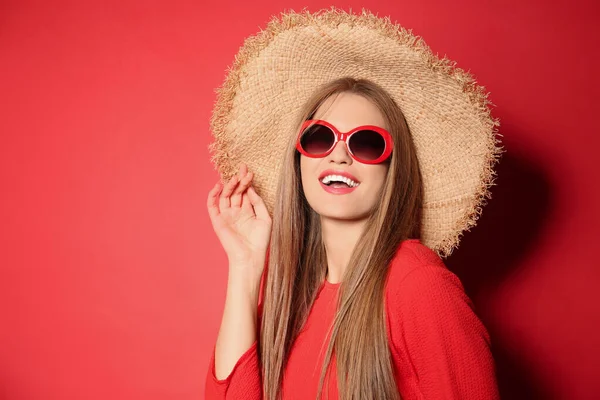 Młoda kobieta w stylowych okularach przeciwsłonecznych i kapeluszu na czerwonym tle. Miejsce na tekst — Zdjęcie stockowe
