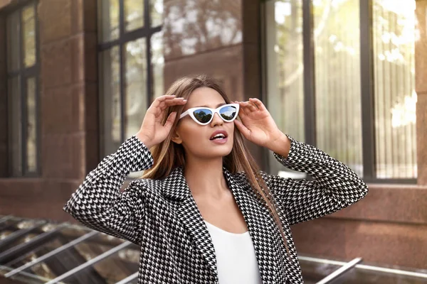 Jeune femme portant des lunettes de soleil élégantes sur la rue de ville — Photo