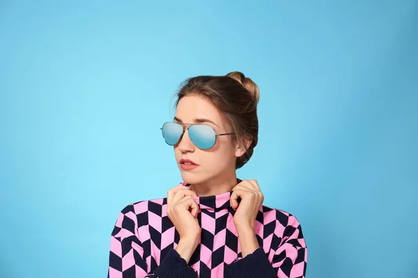 Mladá žena na sobě stylové sluneční brýle na modrém pozadí — Stock fotografie