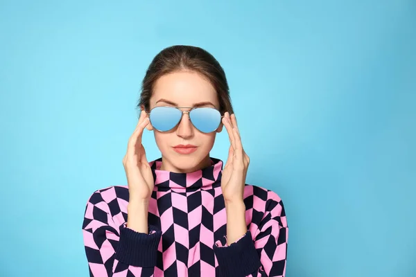 Jonge vrouw draagt stijlvolle zonnebril op blauwe achtergrond — Stockfoto