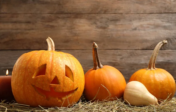 Spooky Jack abóbora cabeça lanterna no feno contra fundo de madeira. Halloween decoração — Fotografia de Stock