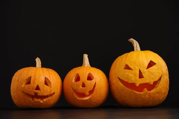 Assustador Jack abóbora cabeça lanternas na mesa cinza contra fundo preto, espaço para texto. Halloween decoração — Fotografia de Stock