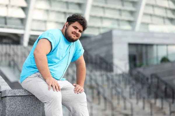 Young overweight man in sportswear resting outdoors — Stock Photo, Image