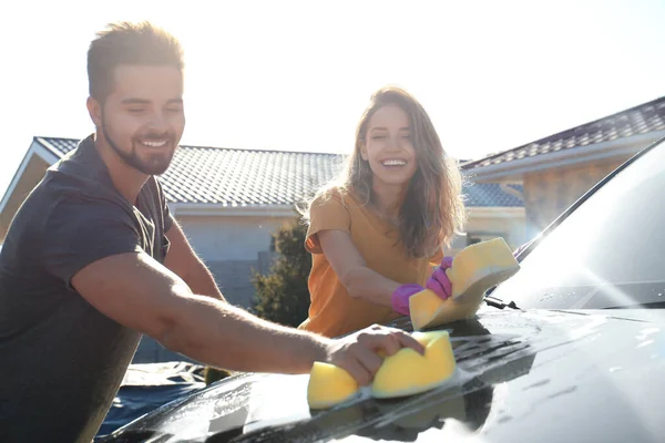 Šťastný mladý pár mytí auta na dvorku na slunný den — Stock fotografie