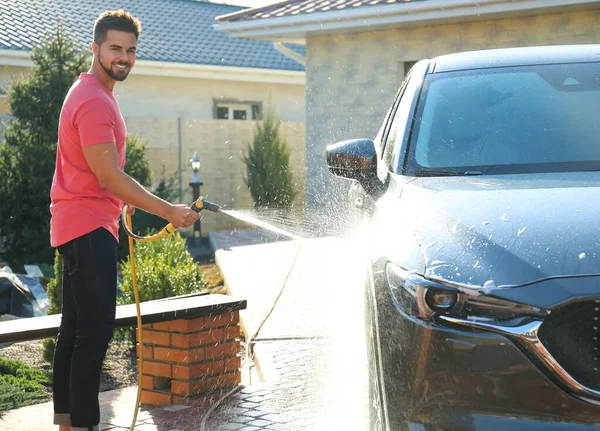Mladý šťastný muž mytí auta na dvorku v slunečný den — Stock fotografie