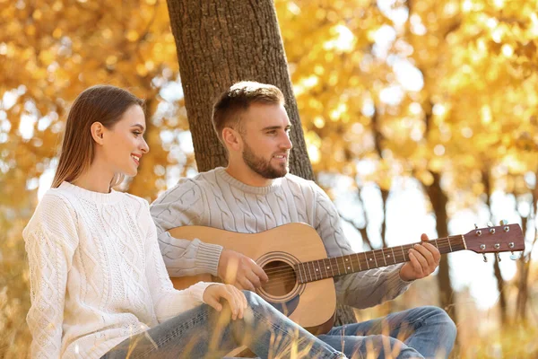 Jeune couple avec guitare dans le parc d'automne — Photo