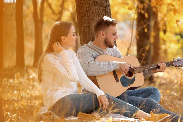 Молодая пара с гитарой в осеннем парке — стоковое фото