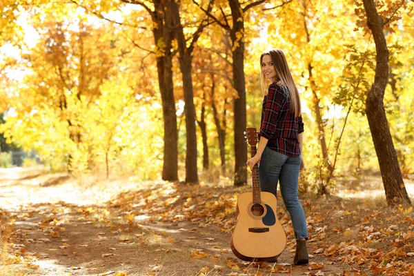 Девочка-подросток с акустической гитарой в осеннем парке — стоковое фото