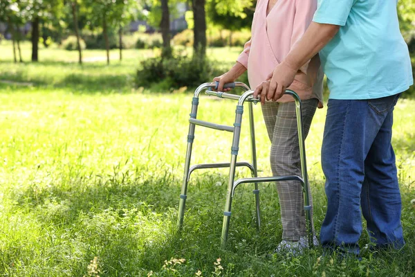 Anciano ayudando a su esposa con el marco de caminar al aire libre, primer plano Fotos De Stock