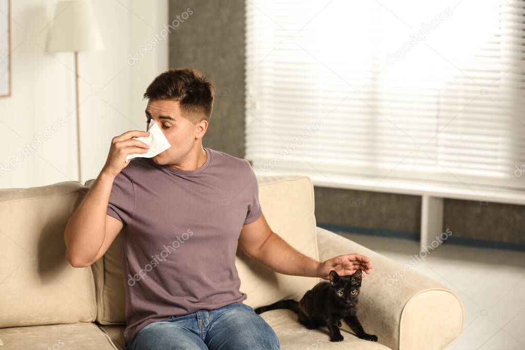 Young man with cat suffering from allergy at home