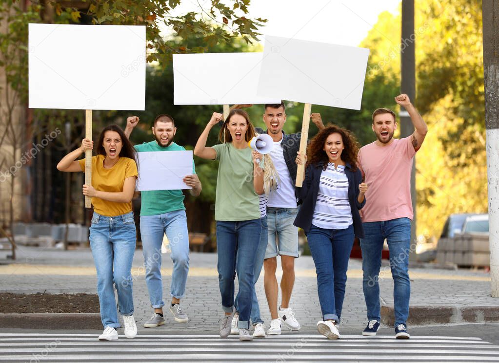 Emotional young woman with megaphone leading demonstration outdoors