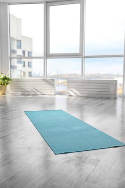 Odada yerde açık mavi yoga minderi var.