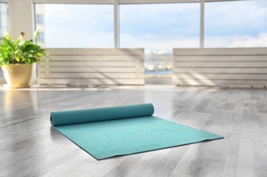 Odada yerde açık mavi yoga minderi var.